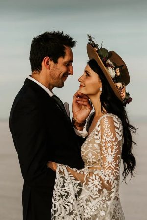 Bride and groom embracing, dressed in suit and a gorgeous boho wedding gown