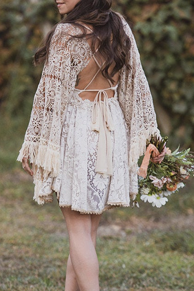 A bride holding a bouquet, wearing a short vintage lace dress made by the designer, Reclamation