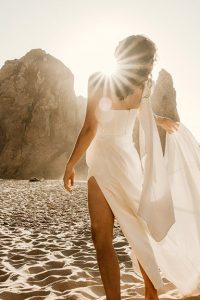 A bride wearing the Luna wedding dress on a beach in Portugal at sunset